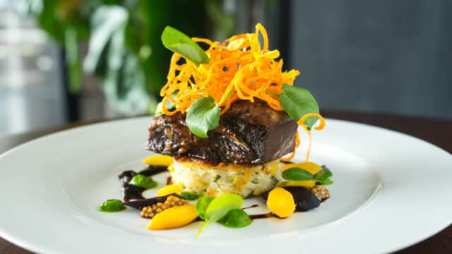 Copy of BRAISED BEEF SHORT RIB 2 Grilled corn scallion cake, tri-colored carrots, spinach silk, mustard seed caviar, organic watercress, yellow pea tendrils, crispy carrot nest and shitake demi (1)